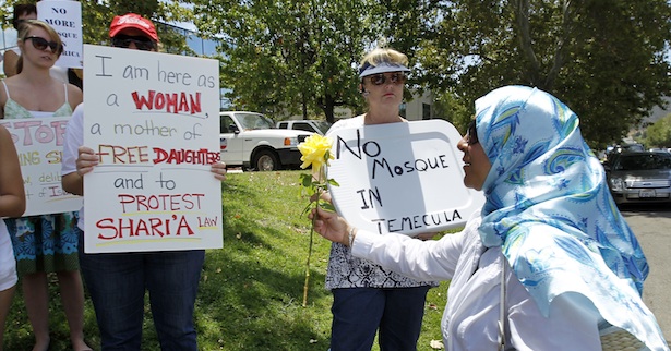 Gabriella Ayoub brings a flower to protesters across the street from her temporary mosque in Temlecula
