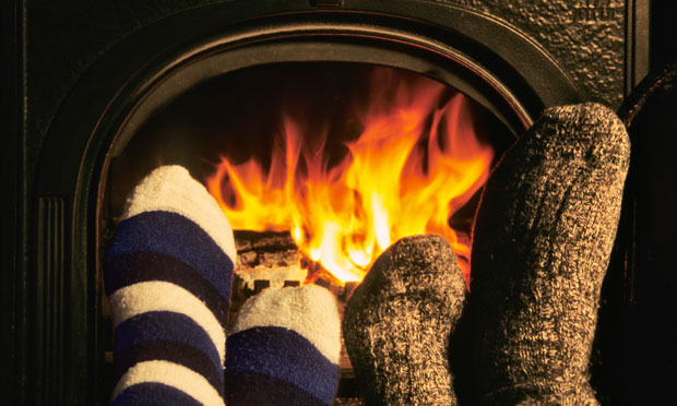 Couple warming feet in front of wood-burning stove