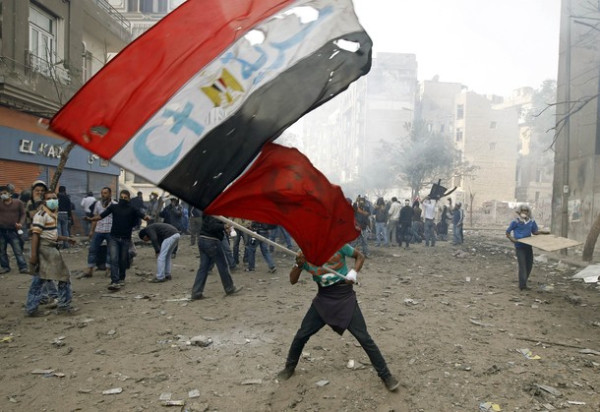A protester waves an Egyptian flag during clashes with riot police in a side street near Tahrir Square in Cairo