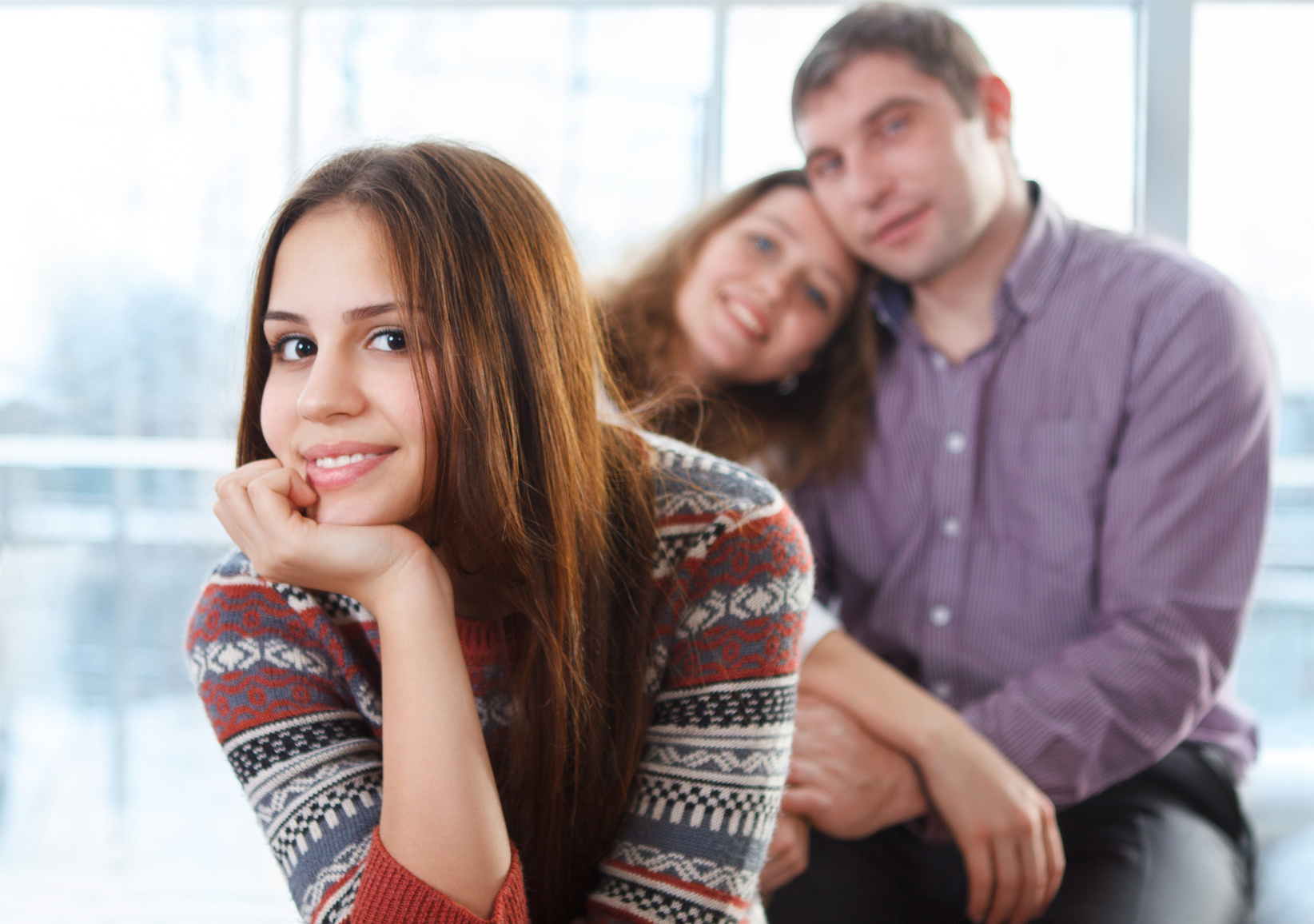 Smiling happy teenage girl sitting in front of her parents