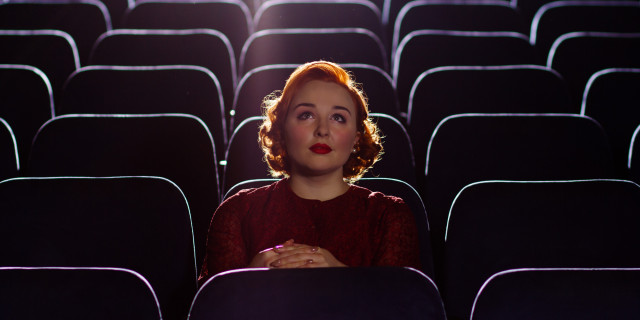 Redhead woman sitting alone in cinema
